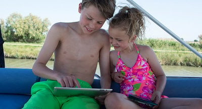 Due bambini che guardano una tablet sul ponte della barca